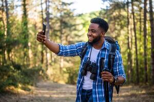 jong Mens geniet wandelen en maken selfie in de natuur. foto