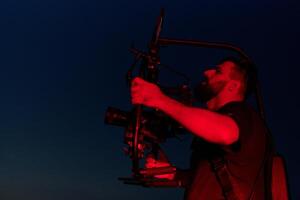 's nachts vastleggen. professioneel videograaf films atleten rennen in rood verlicht duisternis foto