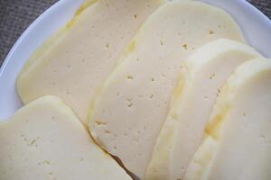 plakjes van kaas besnoeiing Aan een bord. heerlijk kaas met gaten. foto