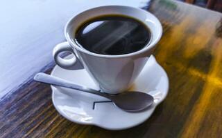 wit kop van zwart americano koffie Aan een houten tafel. foto
