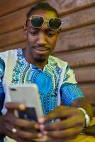 Afrikaanse Amerikaans tiener in traditioneel sudanees kleding verloofd met smartphone foto