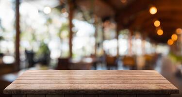 leeg houten tafel top met lichten bokeh Aan vervagen restaurant achtergrond foto