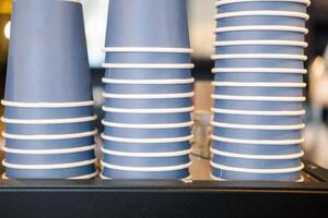 stapel van blauw papier drinken cups netjes georganiseerd Aan koffie machine Bij een cafe. foto