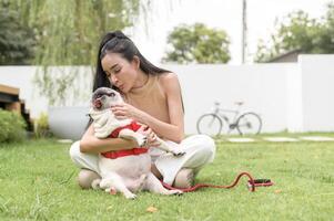 gelukkig Aziatisch vrouw spelen met schattig slim mopshond puppy hond in de achtertuin foto