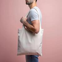 tote zak model. Mens Holding herbruikbaar wit katoen linnen eco biologisch kleding stof canvas blanco totebag Aan roze achtergrond foto