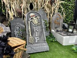 grafsteen halloween platen skeletten hoofd en botten riet Aan kunstmatig groen gras in de achtergrond zijn geschreven Aan de steen Rust in vrede Daar zijn ook gebroken planken, spinnen, manden en kruisen. foto