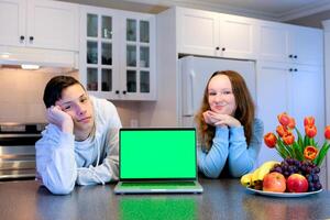tieners jongens meisje in keuken in de buurt een laptop interessant internet sociaal netwerken voedsel ontbijten levering ieder reclame Aan een groen scherm chroma sleutel in adolescentie slank Aan de arm tieners paar foto