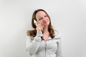 gefrustreerd geërgerd verdrietig vrouw met mobiel telefoon staand binnenkant wit achtergrond foto