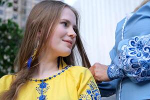 moeder en dochter in geborduurd overhemden blauw en geel blouse schattig familie verhouding detailopname portret gezicht buitenshuis gelukkig senior vrouw genieten van in van dochter genegenheid Aan moeder dag. foto