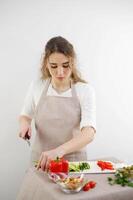 foto portret vrouw in schort aan het kijken recept Aan laptop snijdend komkommer