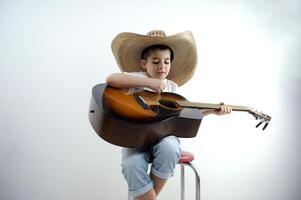 vol vertrouwen houdt een gitaar in zijn handen Aan hoed Toneelstukken een gitaar Aan een wit achtergrond rust uit ontspanning een musical instrument op te slaan een kleding op te slaan voor kinderen hoofddeksels kleuterschool tijd naar school- foto