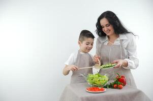 mam en zoon voorbereidingen treffen salade identiek beige schorten groenten komkommers zijn gegoten kind verhouding zorgzaam voor familie wit achtergrond ruimte voor tekst banier advertentie fruit en groente op te slaan supermarkt foto