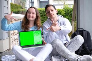 mensen, opleiding, technologie en school- concept gelukkig studenten met laptop computer Chroma sleutel laptop zitten Aan veranda punt vinger tiener jongen tiener meisje foto