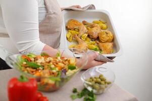 volwassen mooi mollig vrouw voorbereidingen treffen avondeten Aan bakken vel kip poten kwartaal kom met salade noten ingrediënten glimlacht looks shows heerlijk gezond voedsel eetpatroon familie avondeten lunch mam vrouw gastvrouw foto