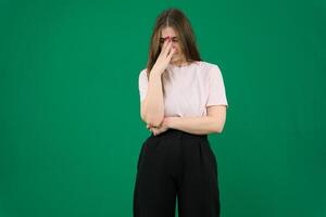 heel van streek, jong Kaukasisch vrouw vervelend zwart t-shirt over- groen achtergrond aanraken neus- tussen Gesloten ogen, wil naar schreeuw, hebben stressvol verhouding of hebben problemen met werk foto