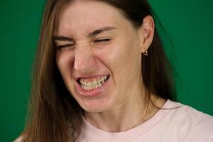 de portret van walgde vrouw verschillend emoties van een jong meisje Aan een groen achtergrond Chroma sleutel mooi gelaats Kenmerken echt mensen roze t-shirt wit gevild. Europese foto