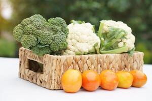 mand van biologisch groenten van tuin. broccoli, bloemkool en tomaten. buitenshuis achtergrond. concept, voedsel ingrediënt. gezond aan het eten, bron van vitamines, vezel en voedingen. vers van tuin. foto