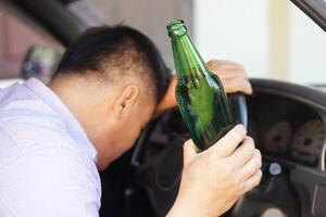 dronken Mens houdt bier fles in auto. concept , campagne voor niet doen drijfveer, niet doen drinken alcohol dat kan oorzaak auto ongeluk en onwettig. gevaarlijk het rijden wanneer dronken. foto