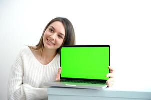 vrouw aan het kijken groen scherm laptop mooi jong meisje in wit trui shows laptop met Chroma sleutel adverteert een Product mooi zo presentatie vreugde winnen uitverkoop mooi hoor positief emoties Aan een wit achtergrond foto