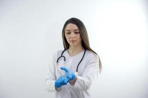 mooi dokter verpleegster vrouw in uniform met stethoscoop, vervelend rubber handschoenen handelen houding, zuurstof masker in medisch ziekenhuis, portret zwart haar, studio verlichting blauw achtergrond kopiëren ruimte foto