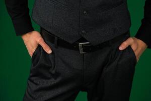 een man's hand- in de zak- van grijs elegant broek detailopname Aan een wit achtergrond. geslaagd jong Mens, zakenman, ondernemer in een duur bedrijf bruin pak, hesje foto