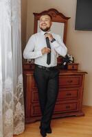 een Mens in een pak en stropdas staat in voorkant van een dressoir foto