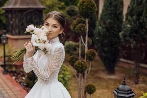 een vrouw in een bruiloft jurk is Holding een boeket van bloemen foto
