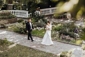 een bruid en bruidegom wandelen naar beneden een steen pad in een tuin foto
