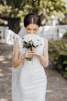 een vrouw in een wit jurk Holding een boeket van bloemen foto