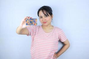 glimlachen gezicht uitdrukking van mooi Aziatisch jong vrouw tonen credit kaart Aan wit achtergrond foto