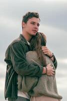 Mens knuffelen een vrouw Aan de strand, staren in de afstand. vangt een moment van overpeinzing binnen een romantisch instelling. foto