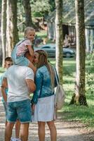 een weinig meisje zitstokken boven haar vader schouders, net zo de familie geniet een vredig dag Bij de park, de essence van zorgeloos weekends gevangen genomen, en familie bonding in natuur. foto