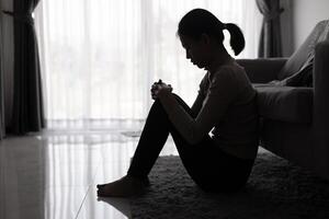 depressief vrouw, silhouet van tiener meisje met depressie zittend alleen in de donker kamer. zwart en wit foto. foto