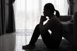 depressief vrouw, silhouet van tiener meisje met depressie zittend alleen in de donker kamer. zwart en wit foto. foto