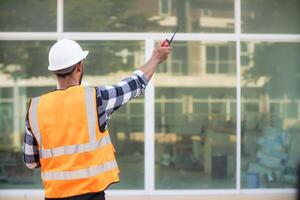 achter de scènes voorman vervelend reflecterende hesje en moeilijk hoed inspecteert bouw plaats naar ervoor zorgen bouw voldoet aan bouwkunde team ontwerp plannen en voor de schoonheid en veiligheid van Bewoners. foto