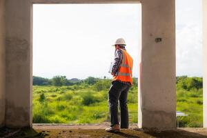 achter de scènes voorman vervelend reflecterende hesje en moeilijk hoed inspecteert bouw plaats naar ervoor zorgen bouw voldoet aan bouwkunde team ontwerp plannen en voor de schoonheid en veiligheid van Bewoners. foto