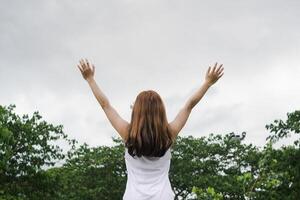 vrouw verheven haar handen bovenstaand haar hoofd naar vragen voor genade van god in overeenstemming met haar geloof in god in Christendom. terug vrouw verhogen beide handen naar vragen voor zegeningen van god volgens naar overtuigingen foto