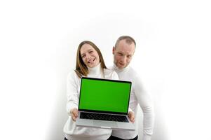 vader en volwassen dochter tonen laptop met blanco scherm ruimte voor tekst meisje shows tong glimlachen pret vreugde grap wit achtergrond wit kleren zilver laptop chroma sleutel groen scherm foto