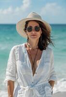 vrouw staand Aan strand met hoed en zonnebril foto