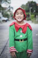 Aziatische kinderen die een rood en groen pak van het thema van de Kerstman dragen dat buiten staat foto