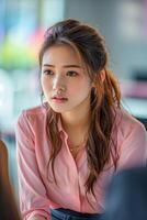 ongelukkig jong Aziatisch vrouw in kantoor, vervelend roze shirt, lang bruin haar- foto