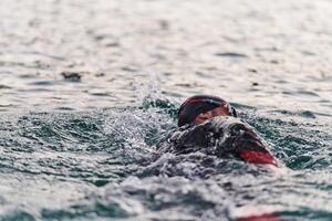 een professioneel triatleet treinen met onwankelbaar toewijding voor een aanstaande wedstrijd Bij een meer, uitstralend een zin van atletiek en diepgaand inzet naar uitmuntendheid. foto