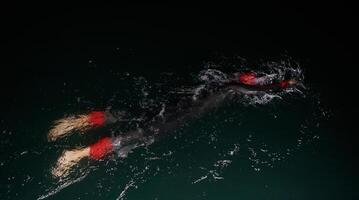 een vastbesloten professioneel triatleet ondergaat rigoureus nacht tijd opleiding in verkoudheid wateren, presentatie van toewijding en veerkracht in voorbereiding voor een aanstaande triatlon zwemmen wedstrijd foto