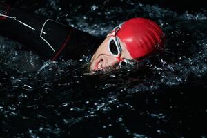 een vastbesloten professioneel triatleet ondergaat rigoureus nacht tijd opleiding in verkoudheid wateren, presentatie van toewijding en veerkracht in voorbereiding voor een aanstaande triatlon zwemmen wedstrijd foto