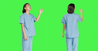 Aziatisch medisch assistent ziet hologram in studio met groene scherm lay-out, werken met holografische beeld en kunstmatig intelligentie. mannetje verpleegster in uniform met gezondheidszorg expertise. foto