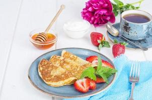 gastronomisch ontbijt. heerlijke zoete gebakken pannenkoeken met verse aardbeien. foto