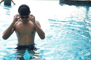 Aziatisch mannen beoefenen zwemmen en voorbereidingen treffen naar Speel water polo en uitrekken en resting voor water sport. foto