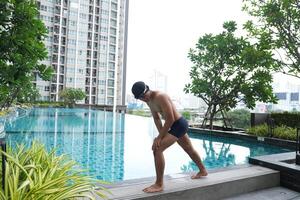Aziatisch mannen beoefenen zwemmen en voorbereidingen treffen naar Speel water polo en uitrekken en resting voor water sport. foto
