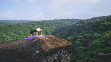 Aziatische vrouwen ontspannen in de vakantie. spelen als yoga. op de berg rots klif. aard van bergbossen in thailand. jonge vrouw die yoga beoefent in de natuur vrouwelijk geluk. yoga beoefenen foto