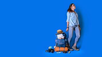 jonge Aziatische reiziger gelukkige vrouw in blauw shirt met rugzak met en uitrusting voor reizigers vakantie met een kaart, op blauwe kleur achtergrond. reis rugzak foto